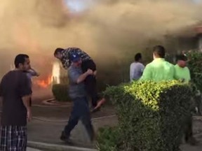 A man is carried from a burning home in Fresno. (YouTube)