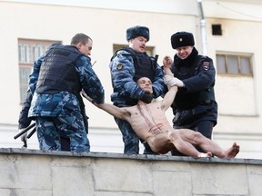 Interior Ministry members detain artist Pyotr Pavlensky after he cut off a part of his earlobe while sitting on the wall enclosing the Serbsky State Scientific Center for Social and Forensic Psychiatry during his protest action titled "Segregation" in Moscow Oct. 19, 2014.  REUTERS/Maxim Zmeyev