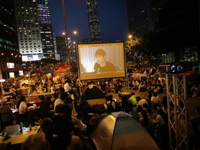 Pro-democracy protesters watch formal talks between student protest leaders and city officials on a video screen near the government headquarters in Hong Kong Oct. 21, 2014. REUTERS/CARLOS BARRIA