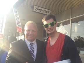 A man calling himself Michael Dunbar Jr. holds a 'folks' election sign alongside Doug Ford at a plaza at Bathurst St. and Sheppard Ave. on Sunday. (Twitter photo)
