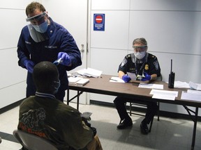 U.S. Coast Guard Health Technician Nathan Wallenmeyer (L) and Customs Border Protection (CBP) Supervisor Sam Ko conduct pre-screening measures on a passenger arriving from Sierra Leone at O'Hare International Airport's Terminal 5 in Chicago, in this handout picture taken October 16, 2014. (REUTERS/U.S. Customs Border Protection/Melissa Maraj/Handout via Reuters)