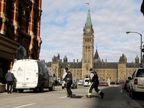 Armed RCMP officers race across a street on Parliament Hill following a shooting incident in Ottawa October 22, 2014. (REUTERS/Chris Wattie)