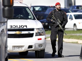 These two armed military police officers screen traffic at the entrance of the passenger terminal at 8 Wing/CFB Trenton, Ont. about one hour after a reservist with the Canadian Forces was shot and killed in Ottawa, Ont., Wednesday, Oct. 22, 2014.- JEROME LESSARD/THE INTELLIGENCER/QMI AGENCY