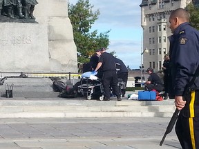 Emergency crews attend to a soldier who was shot while standing guard at Ottawa's War Memorial near Parliament Hill in Ottawa on Wednesday Oct. 22, 2014. An arrest has been made after at least one person was shot in a hail of gunfire on Parliament Hill and the nearby cenotaph. Jon Willing/Ottawa Sun/QMI Agency