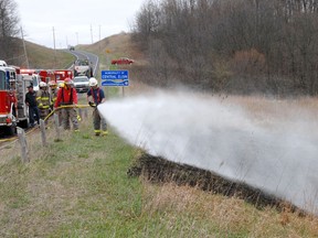Central Elgin firefighters from Union Station douse a grass fire.(ROBERT CHAULK/QMI AGENCY)