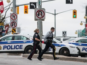 Police officers run near the scene of Wednesday's shooting in Ottawa. QMI Agency