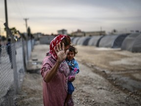A Syrian Kurdish woman walks with her baby on October 23, 2014,  in the Rojava refugee camp at Suruc in Sanliurfa province. (AFP PHOTO/BULENT KILIC)