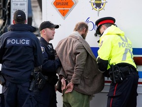 Police officers search a man arrested after approaching police tape near the Canada War Memorial while Prime Minister Stephen Harper paid respect to Cpl. Nathan Cirillo at the Memorial in Ottawa on Oct. 23, 2014. (REUTERS)