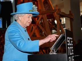 Britain's Queen Elizabeth presses a button to send her first Tweet during a visit to the 'Information Age' Exhibition at the Science Museum, in London October 24, 2014. (REUTERS/Chris Jackson/Pool)