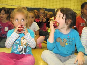 Kaliyah Formosa and Hailey Brooks, kindergarten students at St. Joseph Catholic School in Chatham, bite into some shiny apples as part of the Great Big Crunch on Oct. 23. Over 14,000 apples were delivered to more than 40 schools for the event.