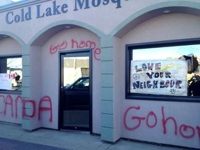 Graffiti covers the front of the Cold Lake mosque after it was vandalized overnight, Oct. 24, 2014. The community later rallied to clean the paint off and post supportive signs over broken windows. (REUTERS/Fraser Snowdon)