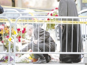 People pay their respects at the National War Memorial in Ottawa Thursday, the day after a gunman?s rampage in the Canadian capital and Parliament buildings left a soldier dead and others wounded.  (Peter McCabe, AFP Photo)