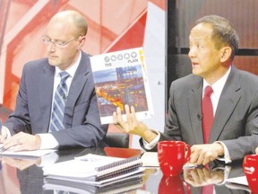 Mayoral candidate Paul Cheng, right, holds up a copy of The London Plan as fellow candidate Matt Brown, left, makes notes during a televised debate at the Rogers TV London studio Tuesday. (CRAIG GLOVER, The London Free Press)