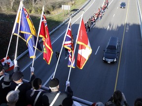 Veterans from the Royal Canadian Legion, Branch 110 in Trenton, Ont. (left) and hundreds of residents wave Canadian flags on the Glen Miller Road overpass as the motorcade bringing Cpl. Nathan Cirillo's body makes its way on Highway of Heroes (Highway 401) bound for Hamilton, Ont. Friday, Oct. 24. 2014.- JEROME LESSARD/THE INTELLIGENCER/QMI AGENCY