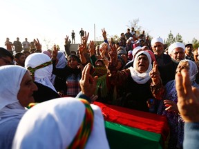 Turkish Kurdish women show the 'V' signs as they mourn during the funeral of three Kurdish fighters killed during clashes against Islamic State in the Syrian town of Kobani, at a cemetery in the southeastern town of Suruc, Sanliurfa province October 24, 2014. REUTERS/Kai Pfaffenbach