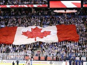 A large Canadian flag is passed through the crowd at the Air Canada Centre at the opening game of the season in Toronto on Oct. 5, 2013. (Michael Peake/Toronto Sun files)