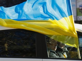 People drive in a car with a national Ukraine flag in the town of Slavyansk, October 25, 2014. Ukraine holds a snap parliamentary election on Sunday, ordered by President Petro Poroshenko with the aim of clearing out loyalists of ousted Moscow-backed leader Viktor Yanukovich and producing an assembly with a pro-Europe majority. REUTERS/Vasily Fedosenko