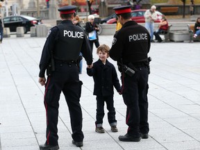 Avery Bruce, 5, shakes hands with two Ottawa Police officers keeping watch at the National War Memorial Saturday, Oct. 26, 2014 where people continued to stop to pay their respects and lay flowers and other items at the monument. (Chris Hofley/QMI Agency)
