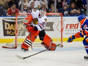 Chicago Blackhawks goalie Scott Darling #33 clear the puck under pressure from Edmonton Oilers left winger Curtis Hamilton #70 during the third period of their NHL preseason game in Saskatoon, Saskatchewan, Sept 28, 2014.  The Chicago Blackhawks defeated the Edmonton Oilers 5-0. /QMI Agency