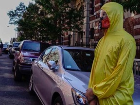 A man wearing personal protective equipment (PPE) as a Halloween costume, stands in front of the building where Dr. Craig Spencer lives in New York October 25, 2014.   REUTERS/Eduardo Munoz