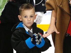 Cpl. Nathan Cirillo's son, Marcus, holds a ceremonial puck at a hockey game where the reservist was honoured. (CRAIG ROBERTSON, Toronto Sun)