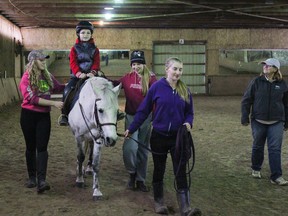 Under the watchful eye of coach Mary De Wolfe, right, eight-year-old Sam Girard rides a horse, Valentine, for the first time during the open house at Wolfden Farms Therapeutic Riding School on Sunday. (Julia McKay/The Whig-Standard)