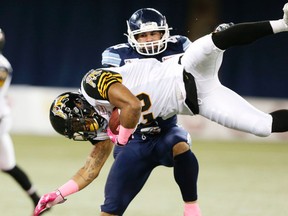 Ticats’ Mossis Madu goes flying as Argonauts’ Shea Emry helps him to the turf during Hamilton’s loss on Saturday in Toronto. The Tabbies are in Ottawa on Friday. (VERONICA HENRI/TORONTO SUN)