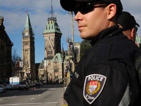 Ottawa police officers, with Parliament Hill in the background, guard the area around the National War Memorial in downtown Ottawa October 23, 2014. A gunman attacked Canada's parliament on Wednesday, with gunfire erupting near a room where Prime Minister Stephen Harper was speaking, and a soldier was fatally shot at a nearby war memorial, jolting the Canadian capital. REUTERS/Blair Gable