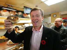 John Tory holds a twister bagel at Bagel World on Wilson Ave. in North York on Sunday, October 26, 2014. (Michael Peake/Toronto Sun)