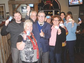 A victorious Joe Baptista (centre) gives the thumbs up following his landslide victory to become mayor of the Township of Leeds and the Thousand Islands. His supporters hold up Air Miles cards – a humorous symbol of the Baptista campaign after his opponent, deputy mayor Heidi Conarroe, asked voters: 'If you are on a plane and the pilot is sick, whom would you want to land it? The trusted co-pilot or the passenger with the fr​equent filers' card.' (WAYNE LOWRIE/The Recorder and Times)