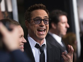 Cast member Robert Downey Jr. crosses his fingers as he poses with his wife and producer of the movie Susan Downey at the premiere of "The Judge" at the Academy of Motion Picture Arts and Sciences in Beverly Hills, California October 1, 2014. (REUTERS/Mario Anzuoni)