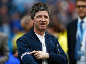 Noel Gallagher singer and Manchester City fan shows off the captains' arm band, given to him by Vincent Kompany, as he celebrates winning the English Premier League trophy following their soccer match against West Ham United at the Etihad Stadium in Manchester, northern England May 11, 2014. (REUTERS/Darren Staples)