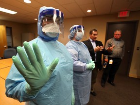 Alberta Health Services' Dr Mark Joffe (2nd from r) and Dr. James Talbot (far r) shows what health care workers would wear in a Ebola case during a news conference in Edmonton, Alberta onTuesday, October 26, 2014. Perry Mah/Edmonton Su