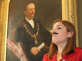 Sporting her own moustasche, Martha Kroeker leads city staff on a tour of portraits of the bearded and moustachioed mayors of the city of Kingston over the years, a Movember project.  Behind her is the portrait of John Gaskin, who was mayor in 1882. (Michael Lea/The Whig-Standard)