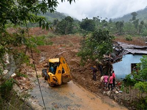 Sri Lankan residents stand outside a damaged building at the site of a landslide caused by heavy monsoon rains in Koslanda village in central Sri Lanka on October 29, 2014. AFP PHOTO/ Ishara S. KODIKARA