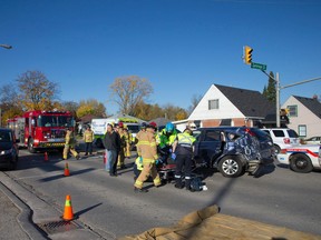 Paramedics and firefighters tend to a woman after the SUV she was driving was struck by a dump truck at the intersection of Oxford and Gammage Streets shortly before 10 a.m. in London on Wednesday October 29, 2014.  The woman was taken to hospital with unknown injuries. (CRAIG GLOVER, The London Free Press)