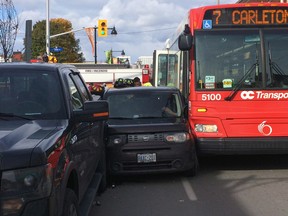 A car is squeezed between a truck and OC Transpo bus on Bank St. Oct. 29, 2014. (Tony Caldwell/Ottawa Sun)