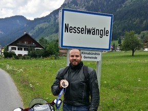 Canadian skier Jan Hudec poses with his Ducati motorcycle in front of a sign with the name of the town where he competed in his very first ski race when he was a boy.
