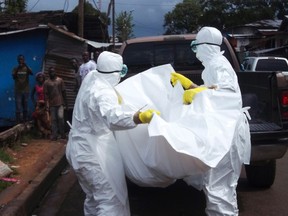 Health workers remove the body of a man believed to have died from the Ebola virus at a street in Monrovia, Liberia, October 27, 2014. REUTERS/James Giahyue