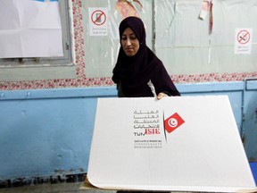 An election worker carries a disassembled cardboard voting booth after the end of voting for the parliamentary elections in Tunis October 26, 2014. Tunisians voted on Sunday in parliamentary elections that bring full democracy finally within their reach, almost four years after an uprising cast out autocrat Zine El-Abidine Ben Ali to inspire the "Arab Spring" revolts. REUTERS/Anis Mili