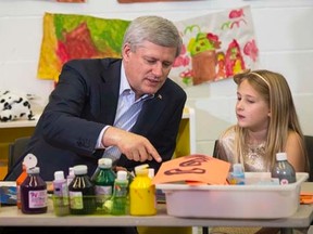 Prime Minister Stephen Harper points while doing arts and crafts with a student at the Joseph & Wolf Lebovic Jewish Community Campus school in Vaughan October 30, 2014.  REUTERS/Mark Blinch