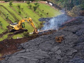 A construction crew tries to contain the lava flow from Mount Kilauea in Pahoa, Hawaii October 29, 2014. The slow-moving river of molten lava from the erupting Kilauea volcano crept over residential and farm property on Hawaii's Big Island on Wednesday after incinerating an outbuilding as it threatened dozens of homes at the edge of the former plantation town. REUTERS/Marco Garcia