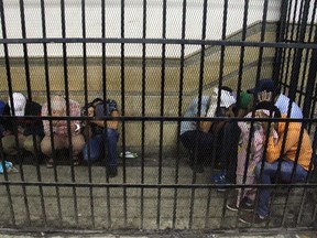 Eight Egyptian men on trial for doing a video prosecutors claimed was of a gay wedding hide their identities as they sit in the defendant's cage during their trial in Cairo on November 1, 2014.  AFP PHOTO / STR