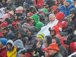 Fans cover up as they watch the Calgary Stampeders take on the Winnipeg Blue Bombers in the snow during a CFL game at McMahon Stadium on November 1, 2014 in Calgary, Alberta, Canada.   Derek Leung/Getty Images/AFP