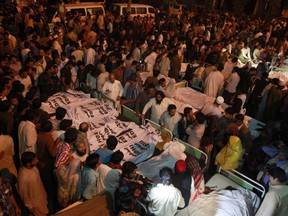 Pakistani relatives gather beside the covered bodies of victims who were killed in suicide bomb attack in Wagha border near Lahore November 2, 2014.  REUTERS/Mohsin Raza