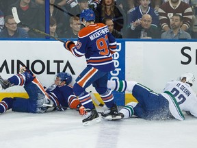 Edmonton forward Taylor Hall (4) crashes into Vancouver forward Daniel Sedin (22) as centre Ryan Nugent-Hopkins (93) looks on during the first period of a NHL hockey game between the Edmonton Oilers and the Vancouver Canucks at Rexall Place in Edmonton, Alta., on Saturday, Nov. 1, 2014. Ian Kucerak/Edmonton Sun