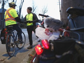 Cycle Kingston volunteer Neal Scott of Cycle Kingston hands out a light to a bicyclist on Union Street during last year's Light My Ride event. The group is planning two light giveaway events next week. (Elliot Ferguson/Whig-Standard file photo)