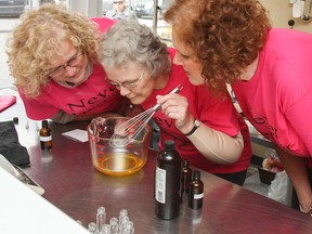 Breast Cancer Action Kingston (BCAK) volunteers Bea Faraklas, Sue Davies and Joy Nielsen inspect the perfume mixture to sample a smell of the new perfume Never Despair, which is being bottled for their fundraiser at the 1000 Islands Soap Company on King Street East on Saturday. Two dollars from each bottle sold will go to BCAK to help with their awareness and programs. (Julia McKay/The Whig-Standard)