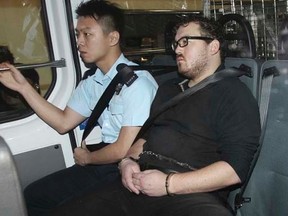 Rurik Jutting (C), a 29-year-old British banker who has been charged with two counts of murder, sits in a police van as it arrives at a court in Hong Kong November 3, 2014.   REUTERS/Apple Daily