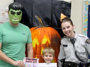 Evergreen Elementary School Grade 1 student Daxton Larson-Jakubowski accepts his Mini Mountie of the Month certificate from Cst. Stephanie Leduc, right, and Cst. Piotr Ulanowski (masquerading as the Hulk in honour of Hallowe’en) on Oct. 31.